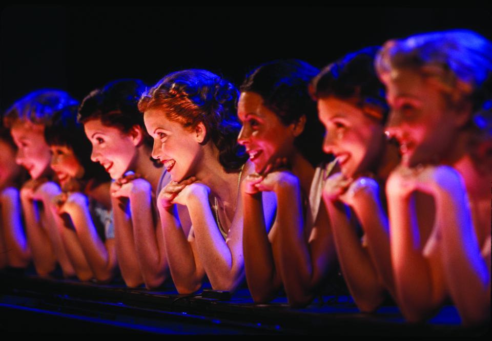 A line of women smiling with their chin in their hands