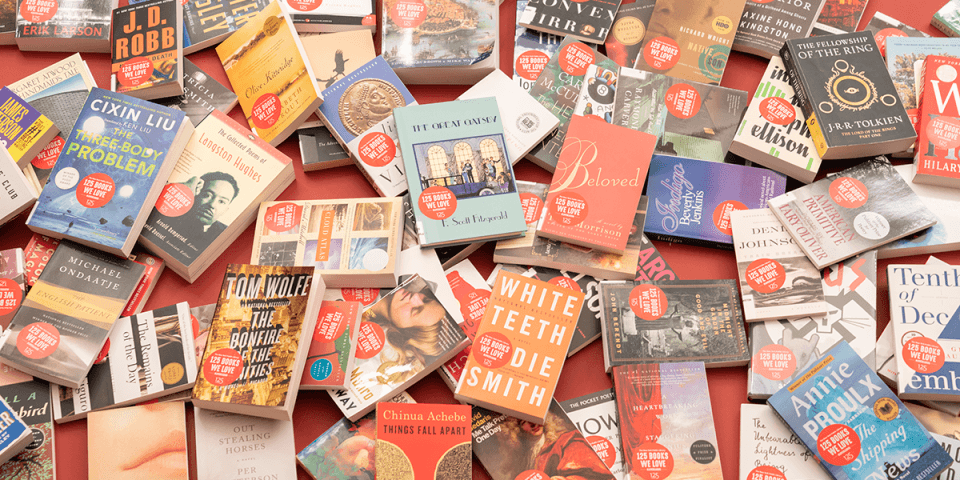 Large amount of books sprawled across a red table.