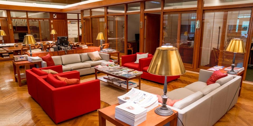 Interior of the Cullman Center, featuring gold lamps, red and cream couches, wooden tables, and offices in the background. 