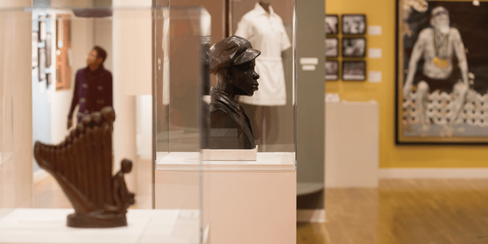 Interior of the Schomburg Center, featuring several statues and paintings inside of an exhibition gallery.