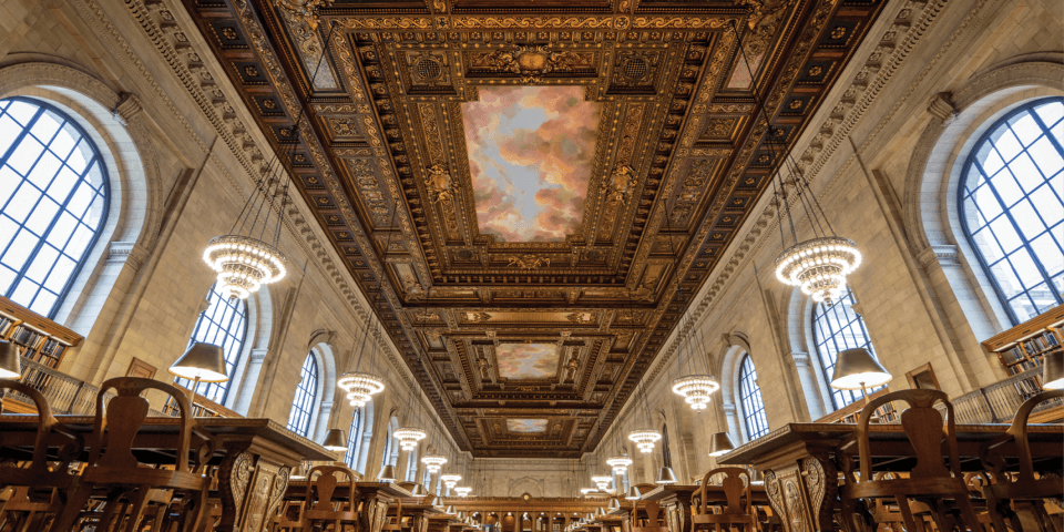 Interior of the Rose Main Reading Room, including an ornate fresco, golden chandeliers, and wooden tables. 