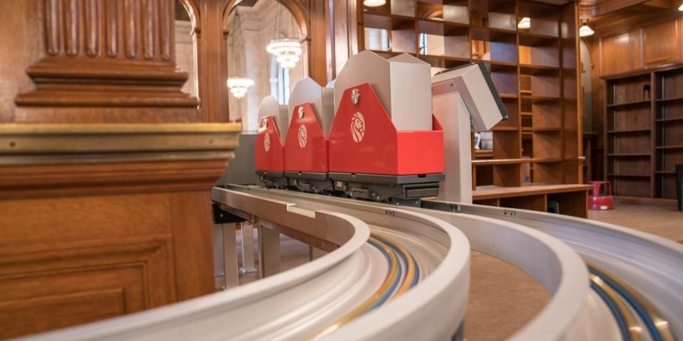 Book carts move along a conveyor belt inside of the Stephen A. Schwarzman Building. 