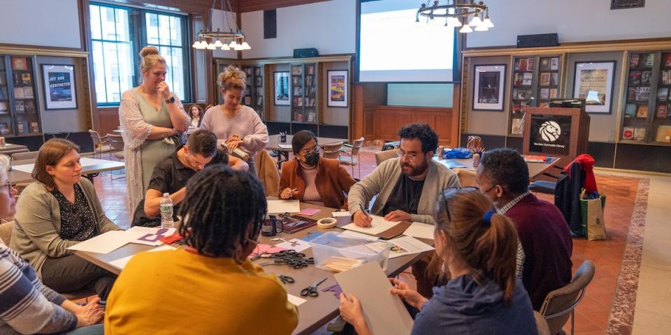 Educators sit around a table participating in a creative writing workshop.