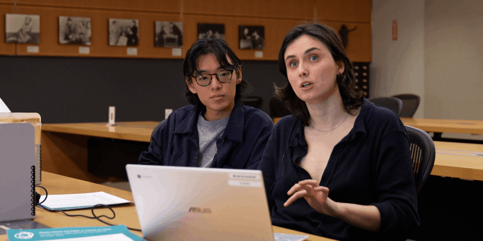 Two people sitting behind a desk with a laptop