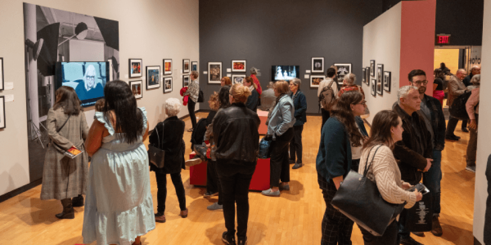 A gallery space with many people looking at the framed images