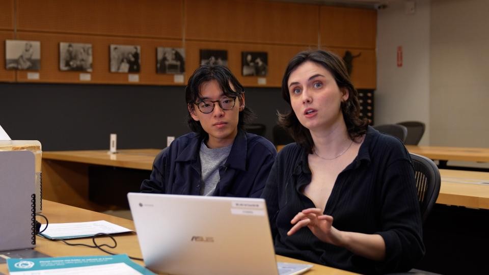 Two people sitting behind a desk with a laptop