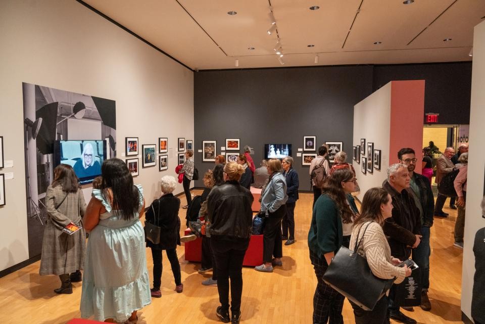 A gallery space with many people looking at the framed images