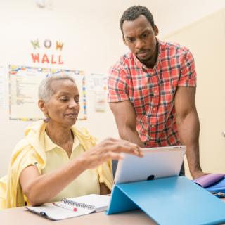 Younger man showing older woman how to use iPad