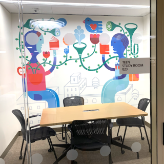 Photo of interior of Teen Study Room with an empty table and four chairs inside a space with a whimsical and colorful mural