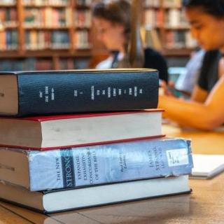 Close-up of a stack of books with researchers working in the background.