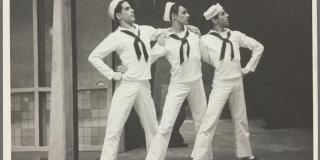 Three men, including Jerome Robbins stand arm in arm with Navy sailor suits