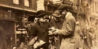 Photograph of shoes-peddler in Lower East Side talking to customers