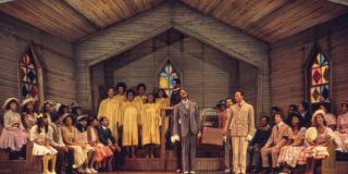 Color photo of people singing on stage in a church.