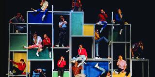 Colorful scaffolding with people standing on it in different poses while on the phone.