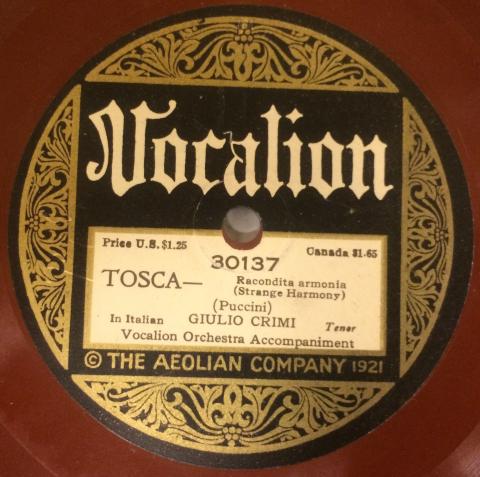 A 1921 Vocalion record is shown, The ornate gold and black label sits atop the red engraved groove surface