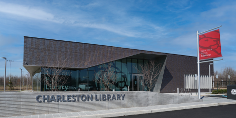 Exterior photo of Charleston Library, featuring a red NYPL banner on a pole in front of the branch.