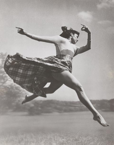 a woman dances through the air as her skirt trails behind her